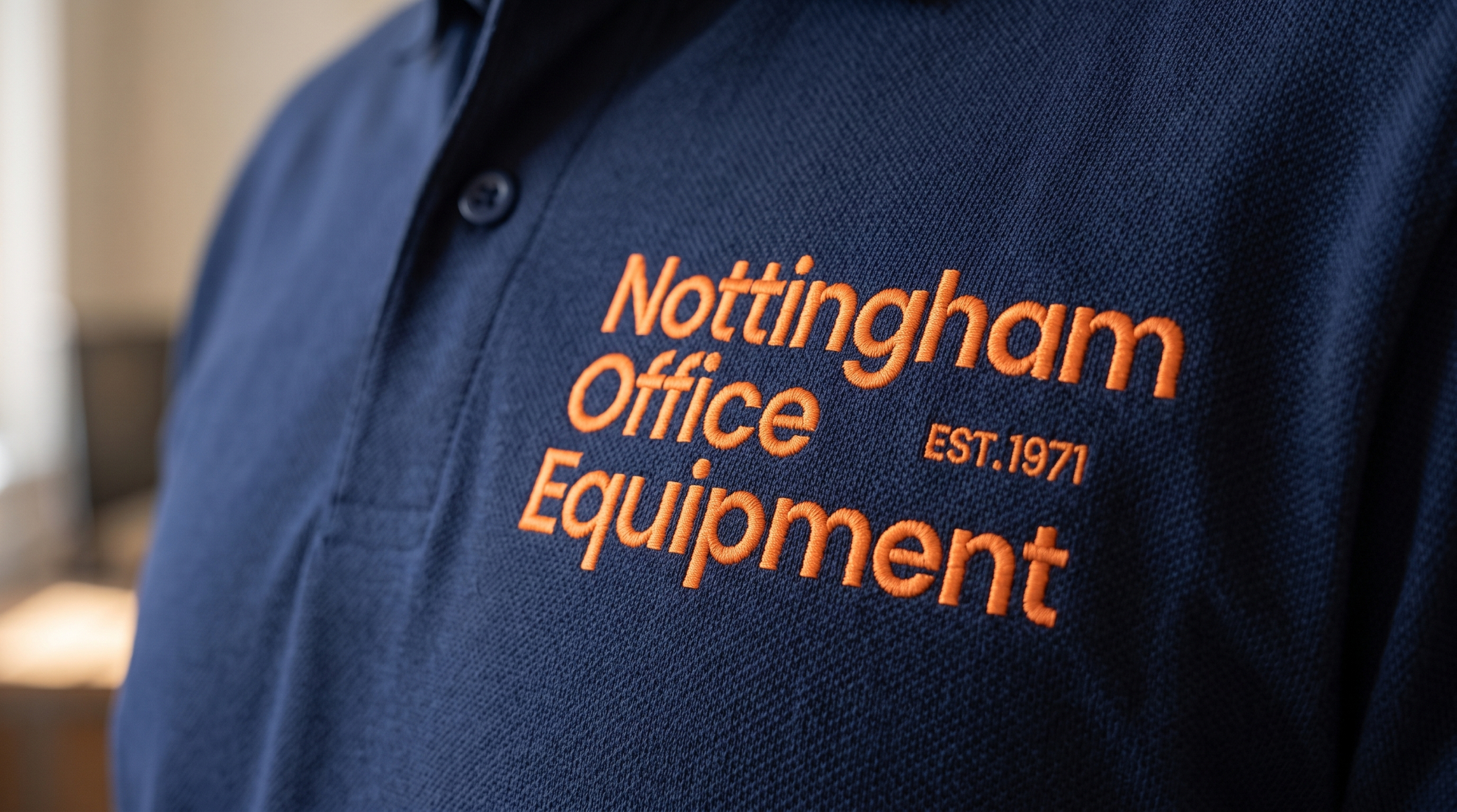 Navy polo shirt with the stacked wordmark embroidered in brand orange